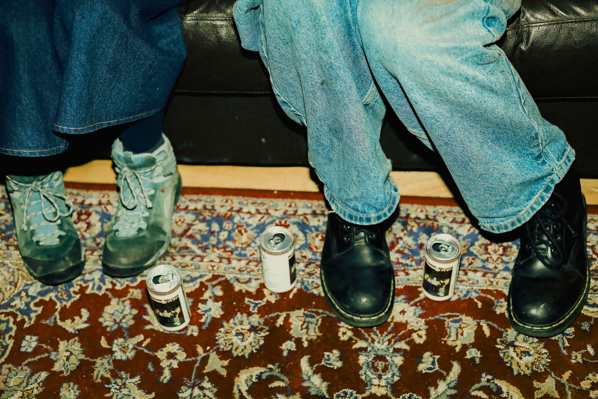SIP cans on a vintage rug between two pairs of boots